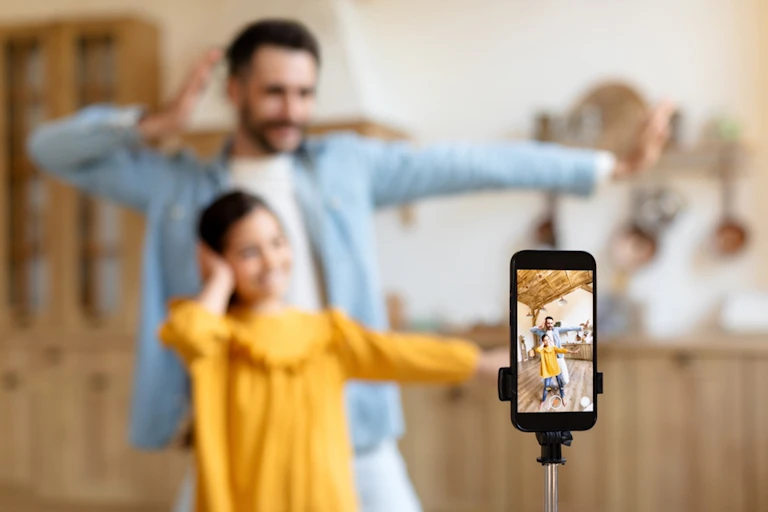 Un père et une fille se filment avec un smartphone
