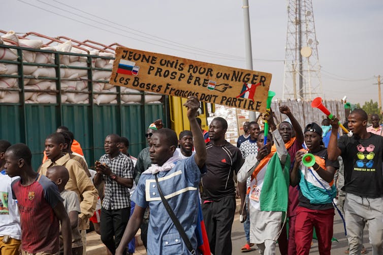 A group of protestors holding a sign that reads ‘French military bases must go’.