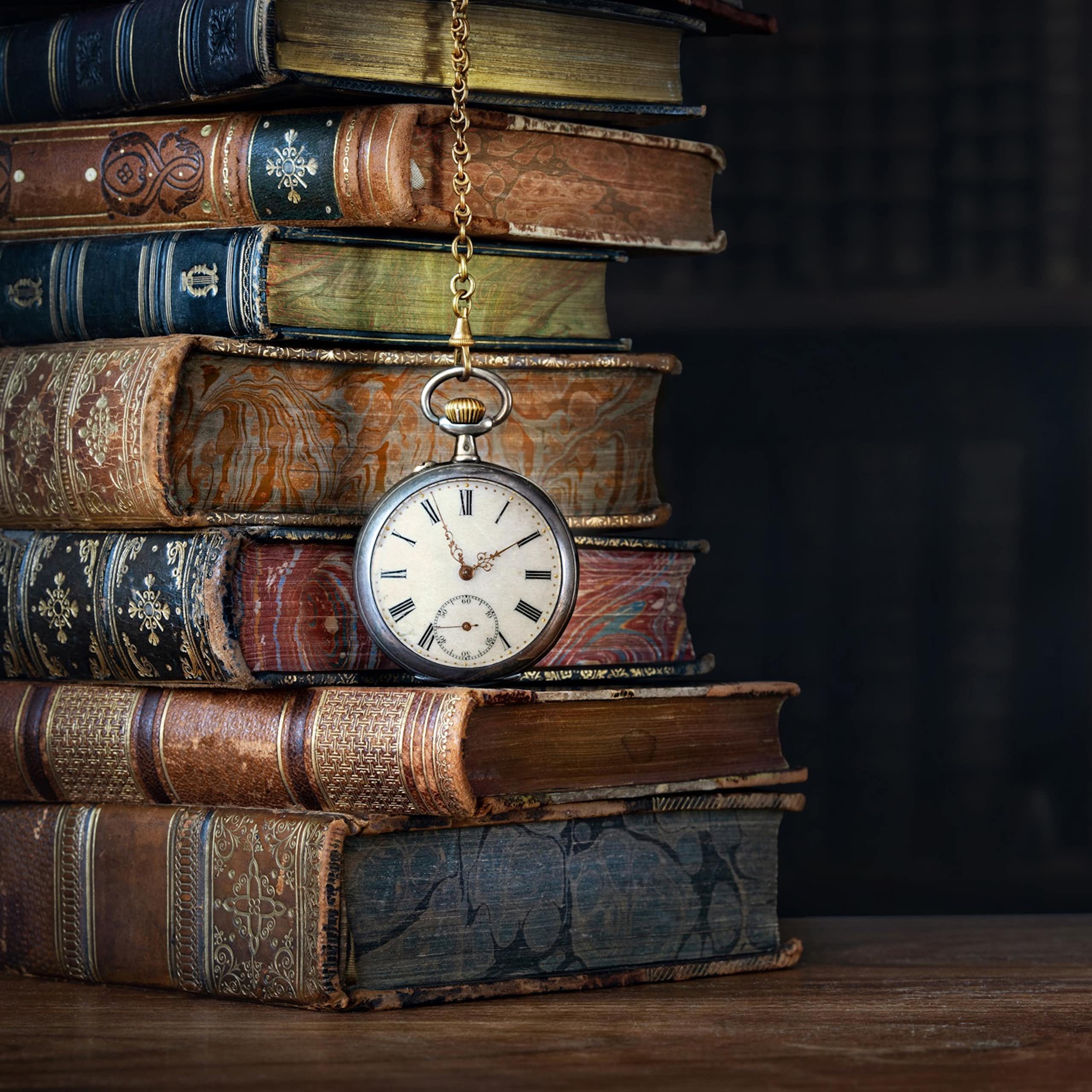 Un reloj de mano colgado en medio de unos libros antiguos.