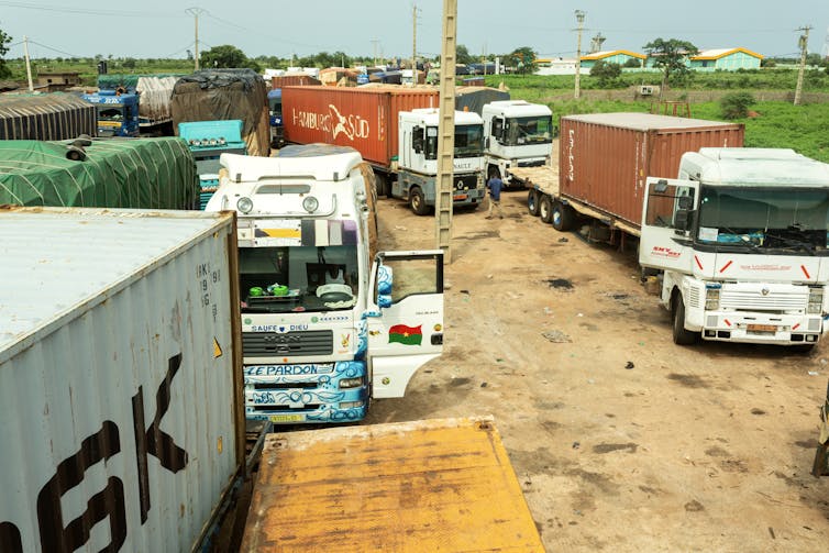 A queue of trucks parked behind each other on a muddy road.