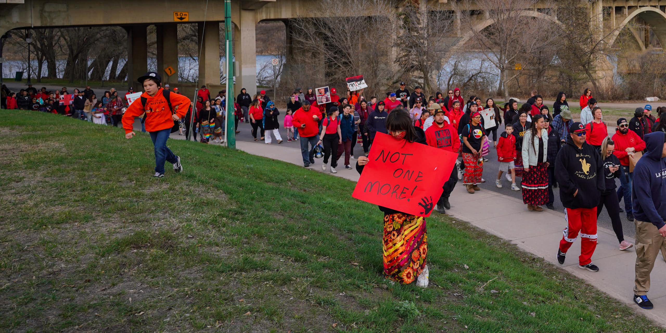 People seen walking wearing red and one person has a sign 'not one more.'