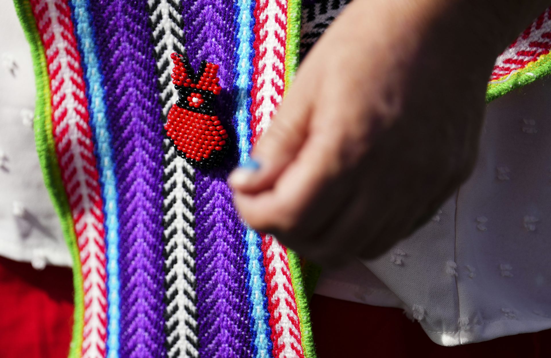 A beaded red dress seen on a colourful sash.