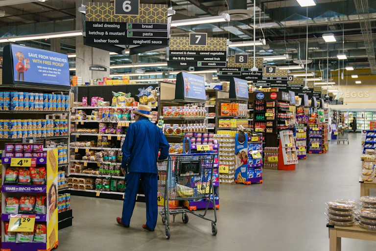 A man in a bright blue suit and jaunty hat shops at a big supermarket.