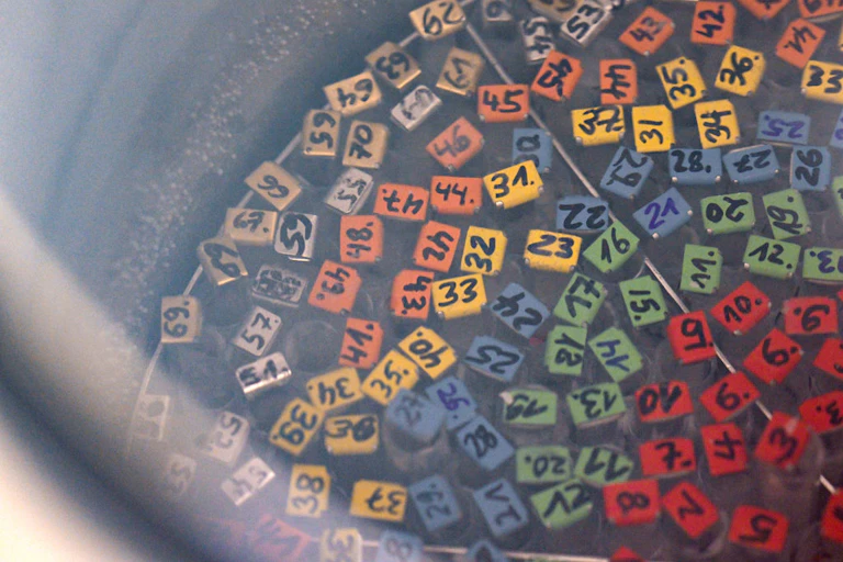 Overhead view of the colorful, labeled tops of numbered test tubes in a foggy silver tank