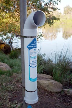 One of the TAngler bins for used fishing line on the banks of the Hawkesbury-Nepean River, which looks like a PVC pipe periscope strapped to a post