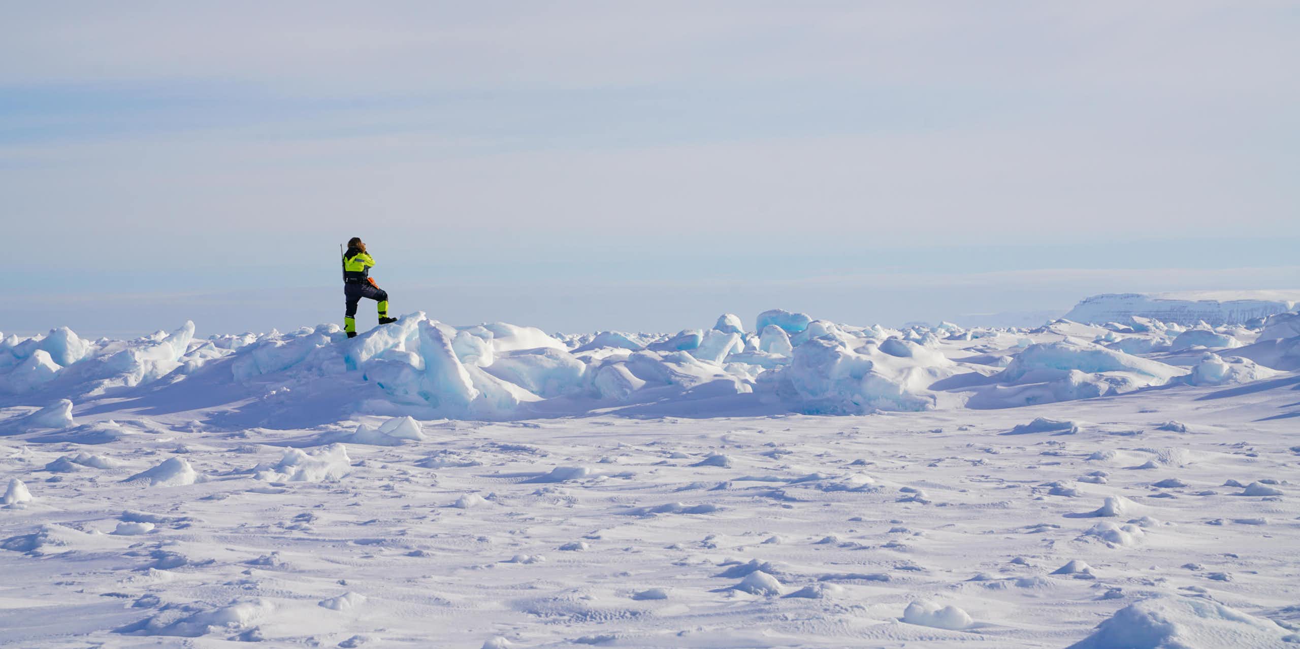 A figure in high vis outfit standing on an icy field