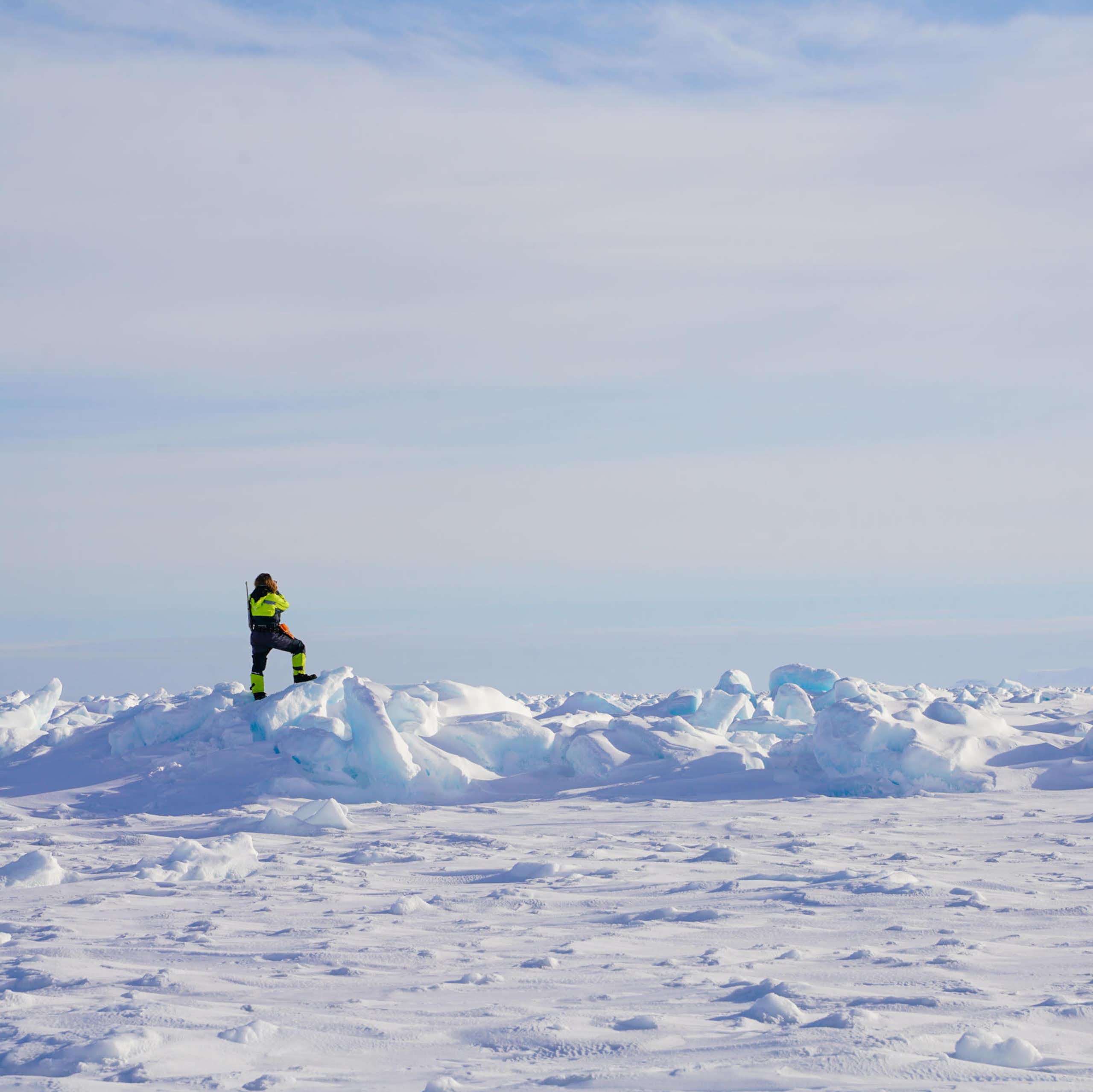 A figure in high vis outfit standing on an icy field