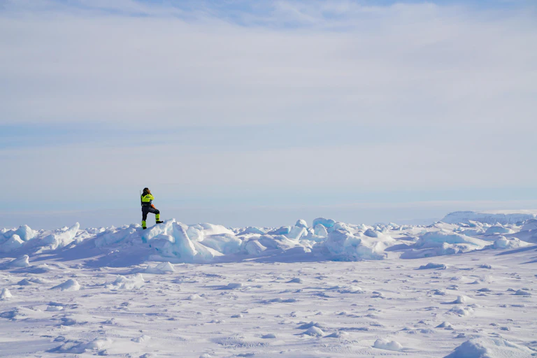 A figure in high vis outfit standing on an icy field