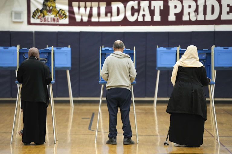 Three voters appear from the back at voting booths.