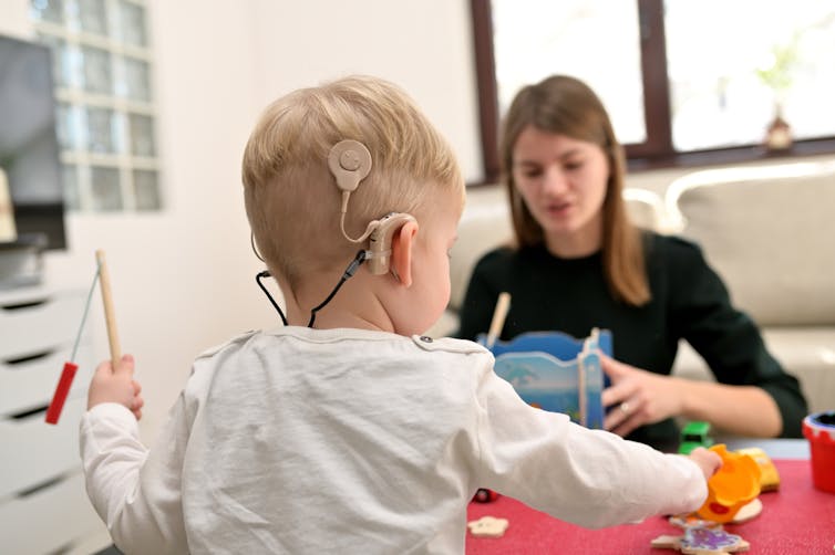 A boy wearing a hearing aid is playing.
