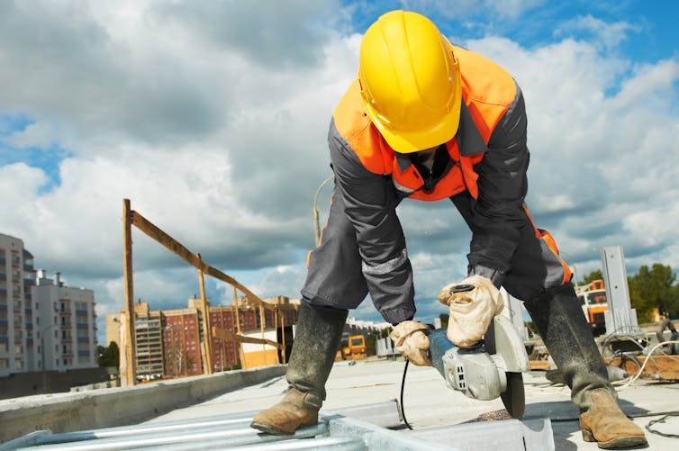 A builder using a grinder machine at a construction site.