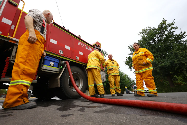 four firefighters stand near truck