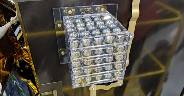 A perspex box of silver spherical objects bolted to a metal panel on a space craft.