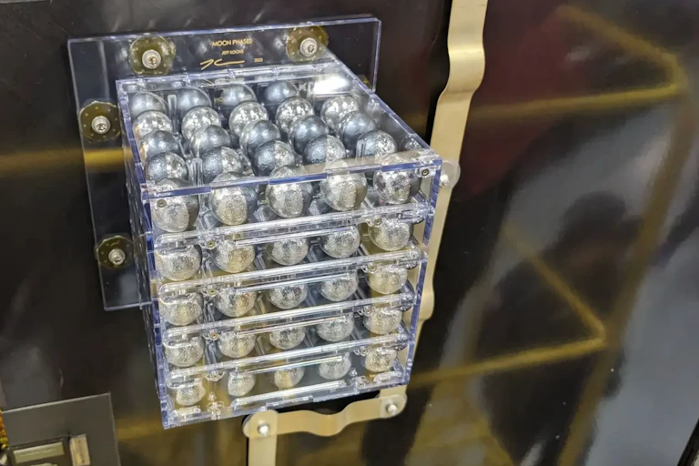 A perspex box of silver spherical objects bolted to a metal panel on a space craft.