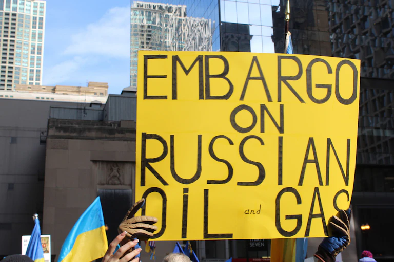 Two people hold a yellow sign saying: embargo on Russian oil and gas.