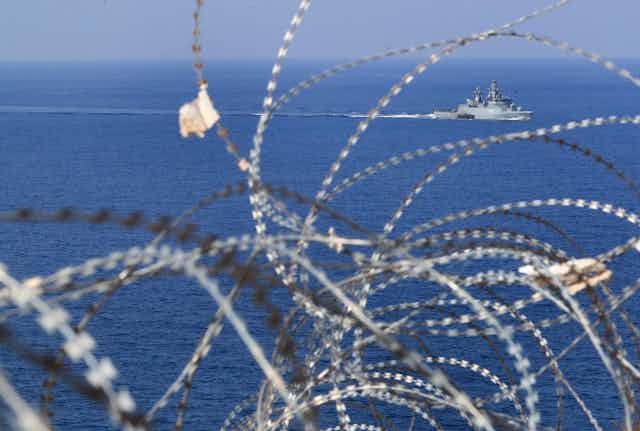 A navy boat seen through barbed wire off the Lebanon coast.