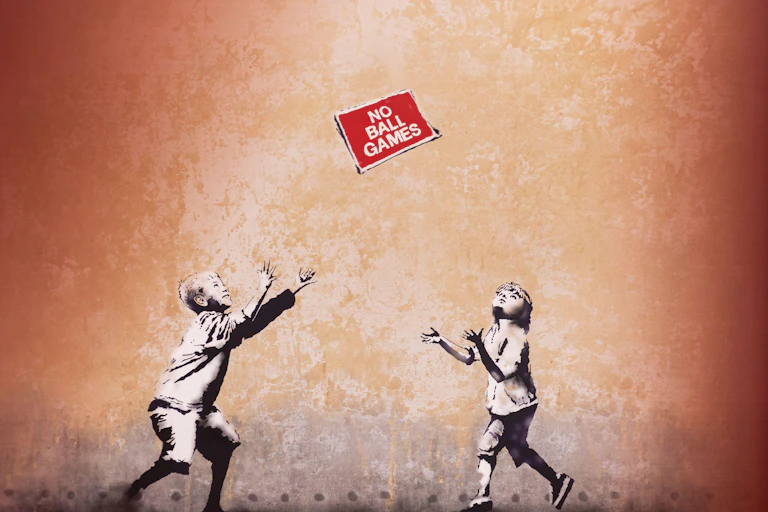 A Banksy mural showing two children throwing a 'No ball games' sign to each other