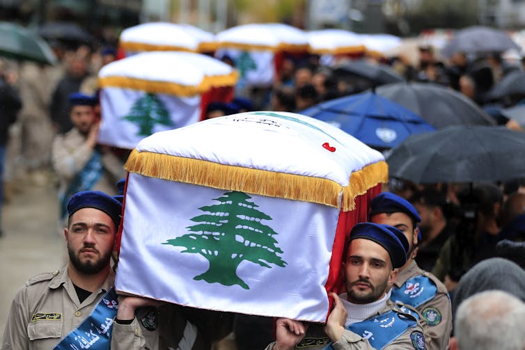 A groupd of mourners carry a coffin.