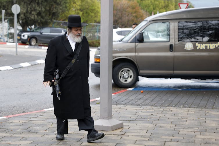 Un hombre vestido con ropas judías ultraortodoxas porta un arma.