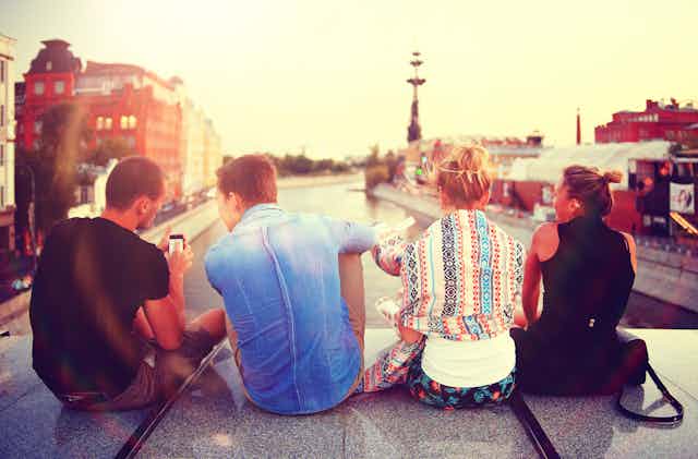 Young people sitting on bridge overlooking city