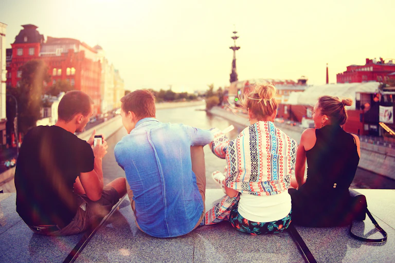 Young people sitting on bridge overlooking city