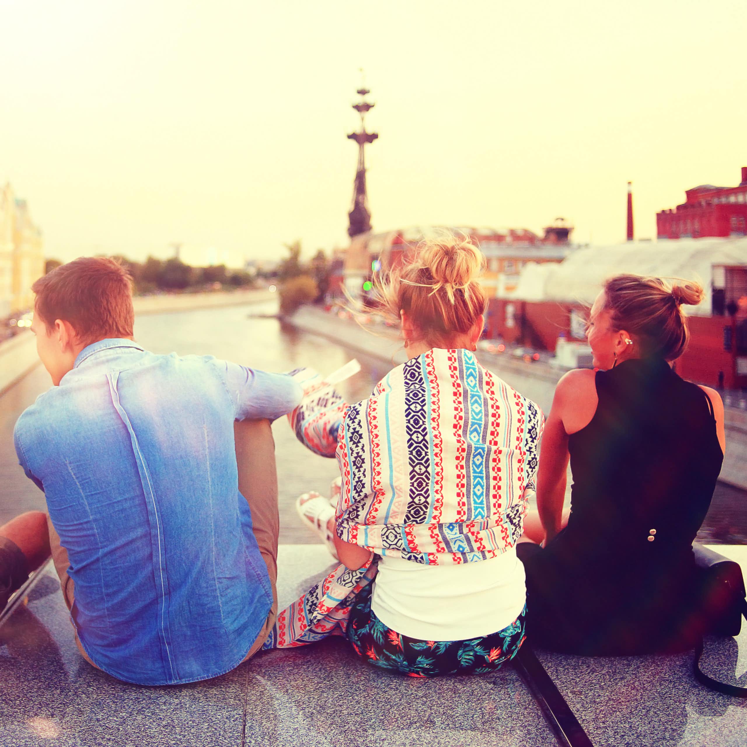 Young people sitting on bridge overlooking city