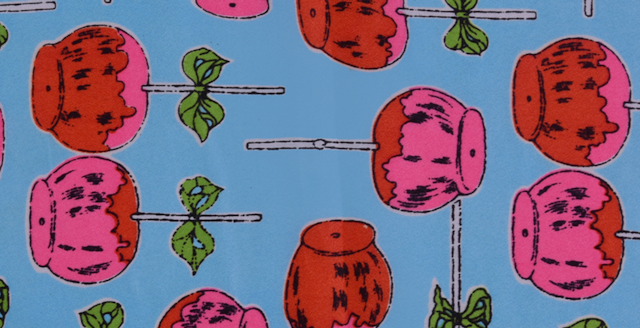 A brightly patterned piece of fabric showing pink lollipops with green bows on a blue background.