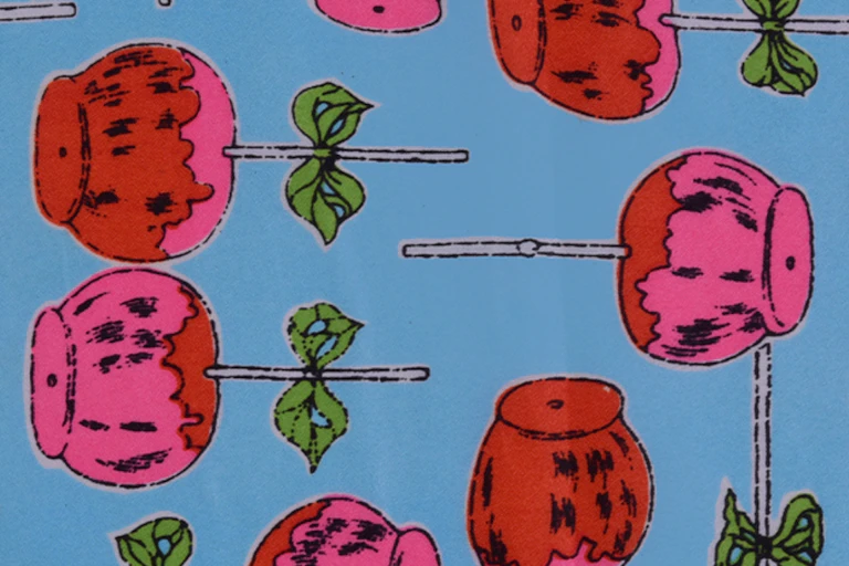 A brightly patterned piece of fabric showing pink lollipops with green bows on a blue background.