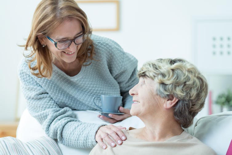 A woman bringing a mug to an older woman