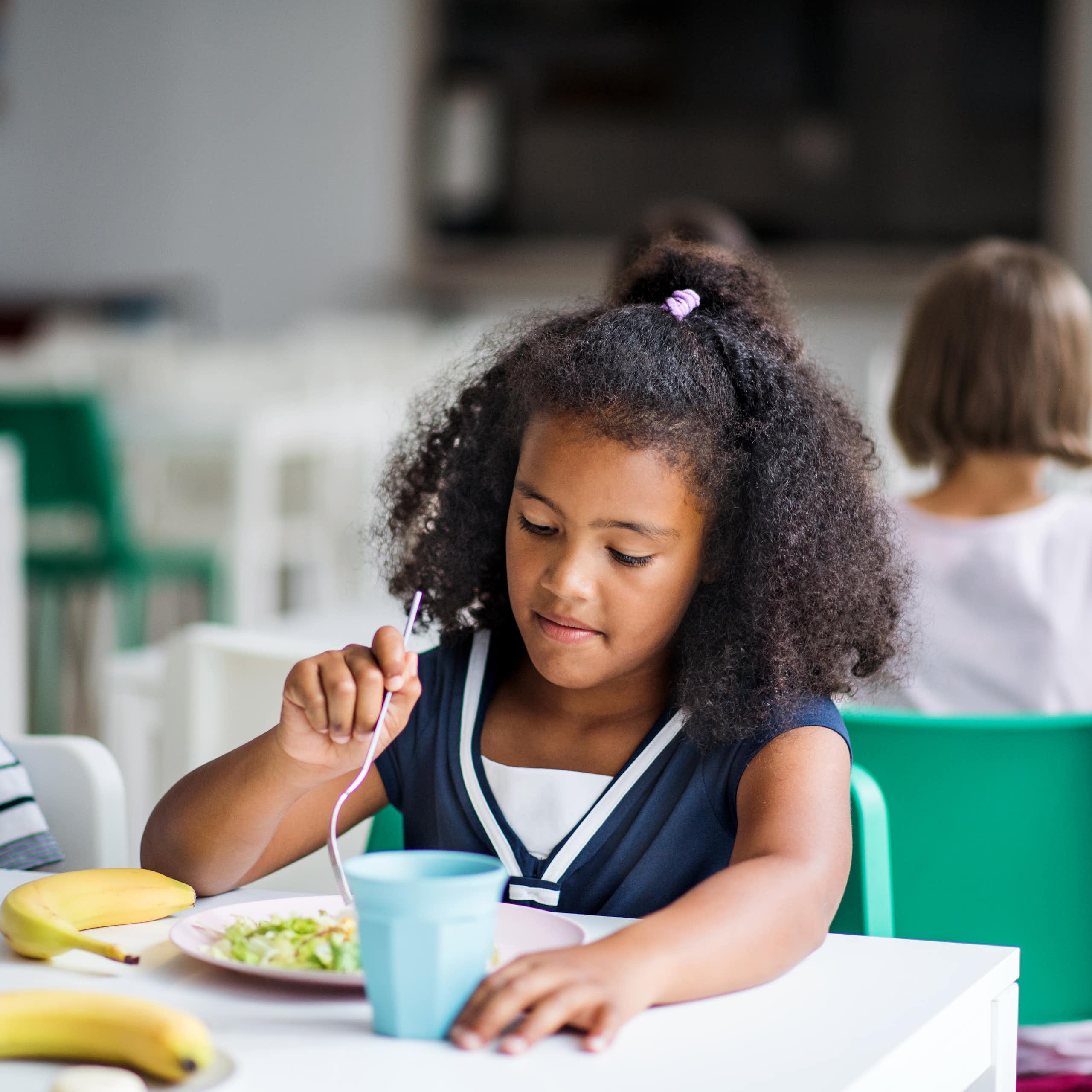 A child eats food off a plate in a classroom