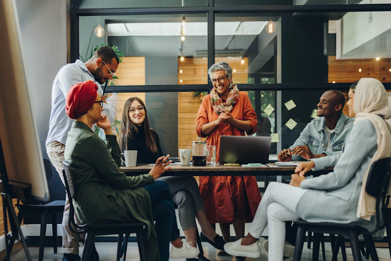 A group of people around a conference table with an easel board in the foreground.