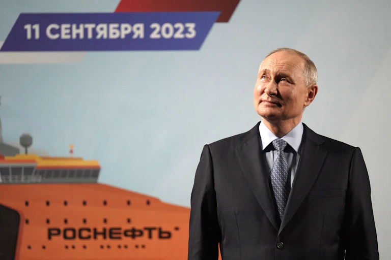 A man in a suit looks wistfully in front of a painting of a boat.