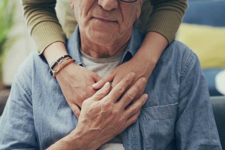 Woman embraces elderly man from behind.