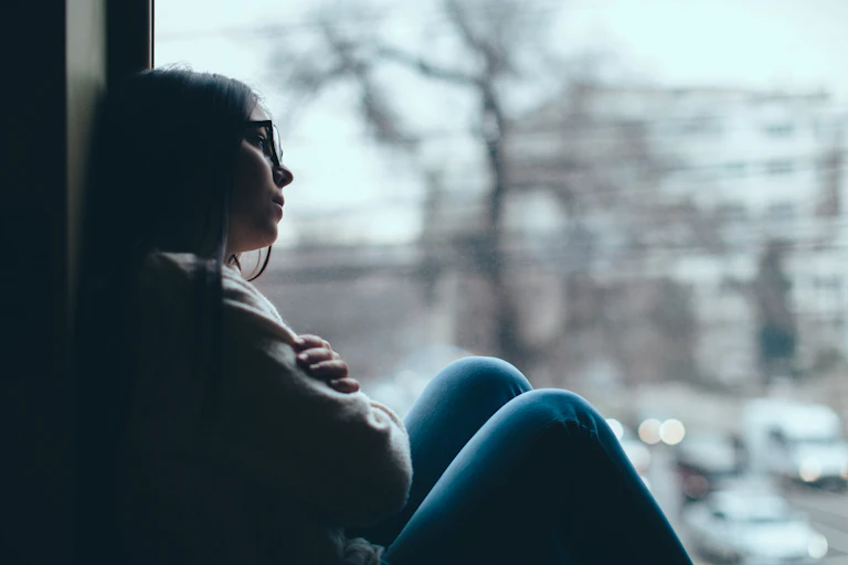A young woman looks out the window, appears pensive.