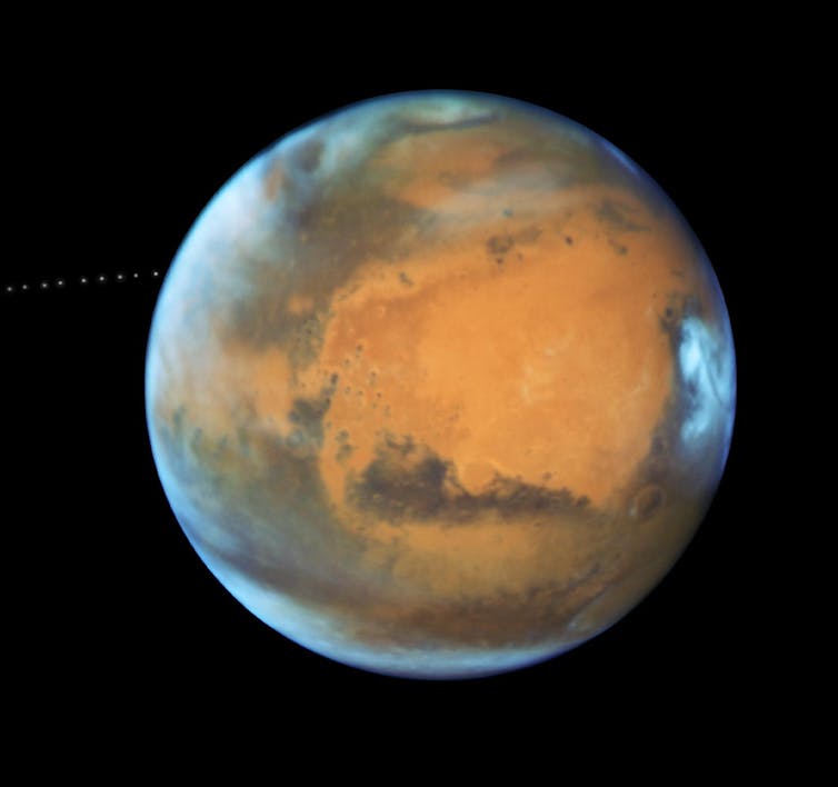 A photograph of the planet Mars, showing white caps and the reddish Martian surface.