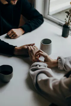 One person holds another person's hand across a table.