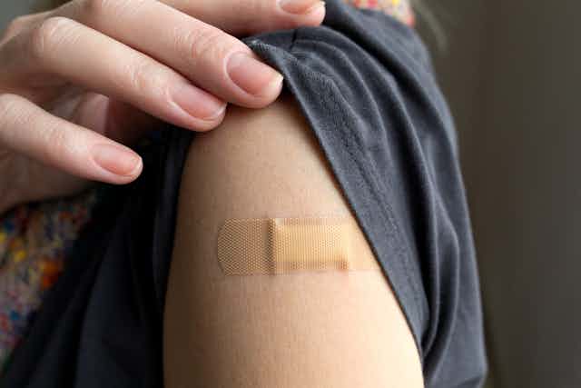 Person shows their bandaid after vaccination