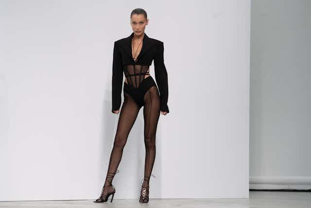Bella Hadid in a black corseted body stocking and cropped blazer.