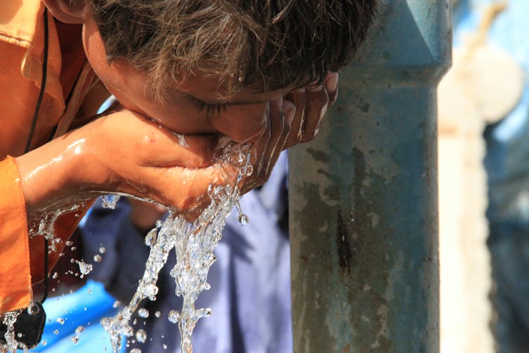 Close up shot of boy drinking clean fresh water from outside tap