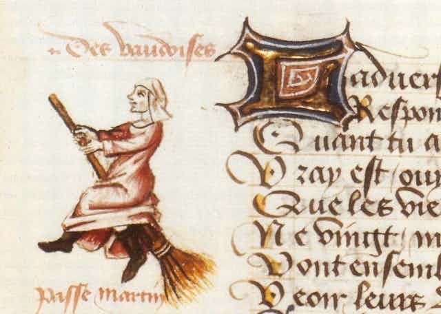 Close-up of a page of a medieval manuscript, with one witch riding a broomstick and another witch riding a staff in the margins