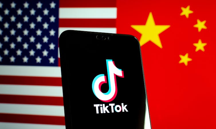 TikTok app logo on a smartphone screen and flags of China and the United States.