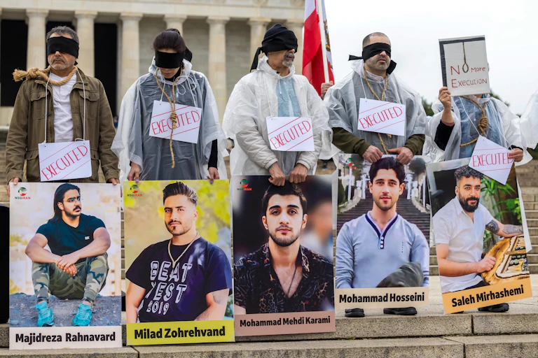 Demonstrators hold up posters of men who were executed in Iran.