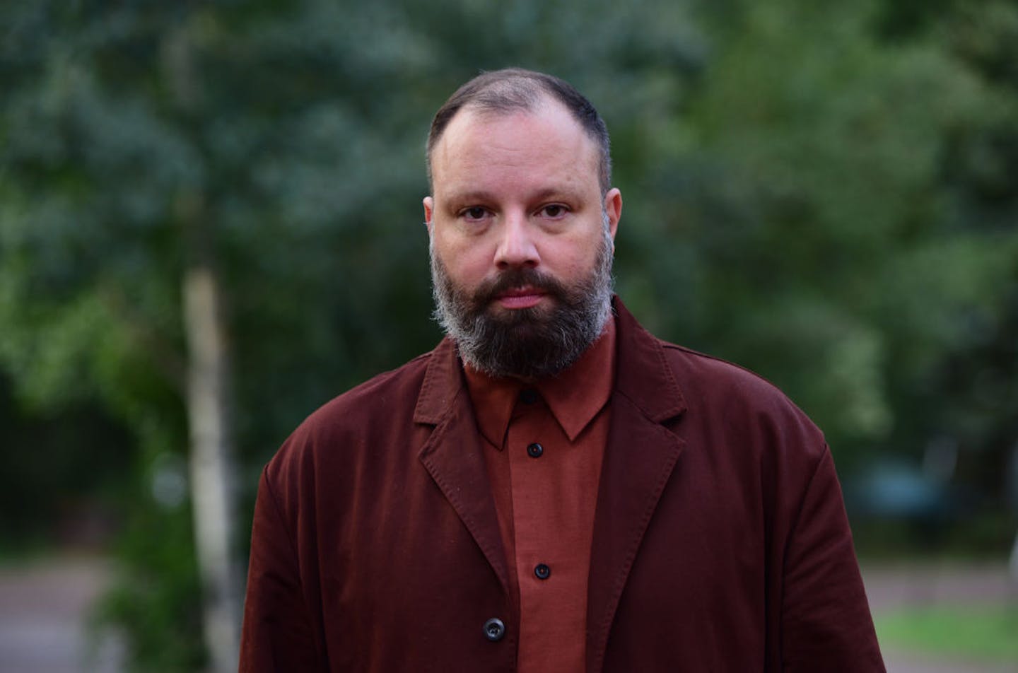 Balding middle-aged man with beard and red jacket.