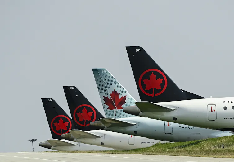 A row of airplane tails with the Air Canada symbol (a maple leaf within a circle) displayed on each