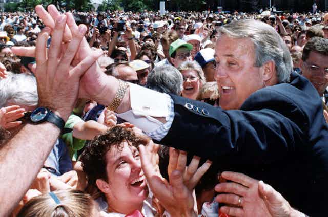 Mulroney wades into a crowd and gives a high five to someone