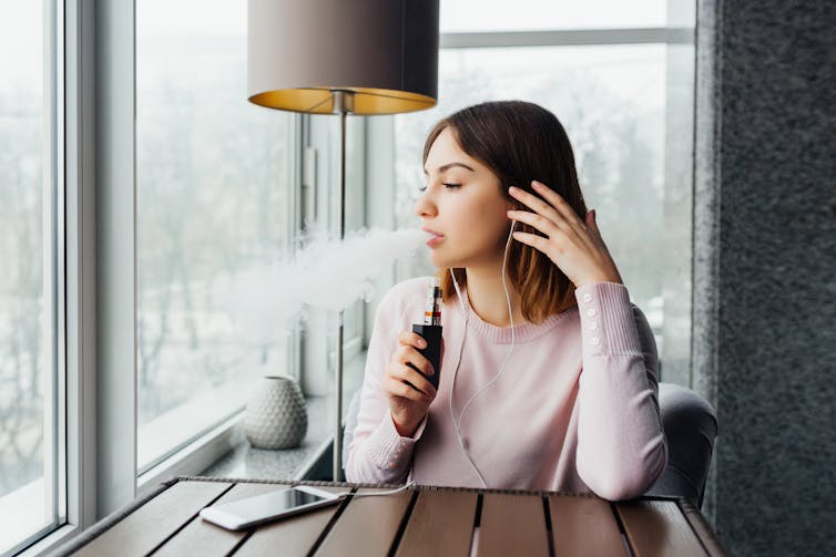 A young woman vaping indoors.