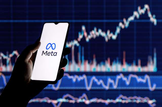 Smartphone with Meta logo on the background of stock chart.