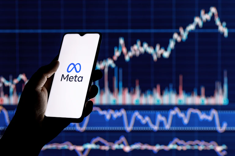Smartphone with Meta logo on the background of stock chart.