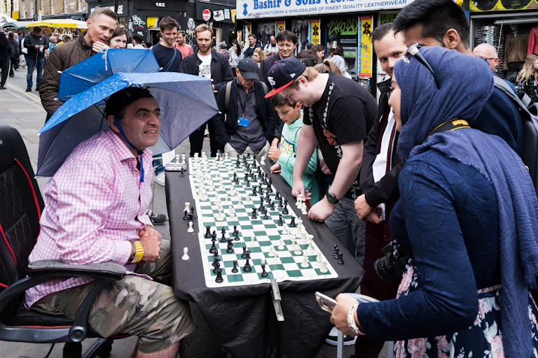 People under umbrellas on a street market.