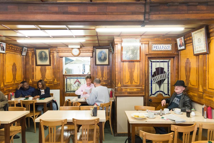 A wood-panelled interior of an east London cafe with customers.